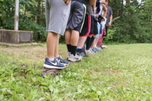 Boys legs standing in a line outside.