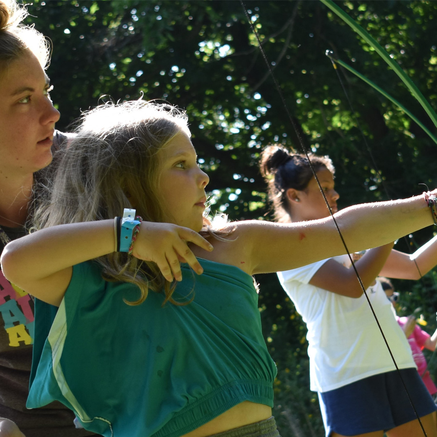 Young girls practicing archery at Camp Kupugani