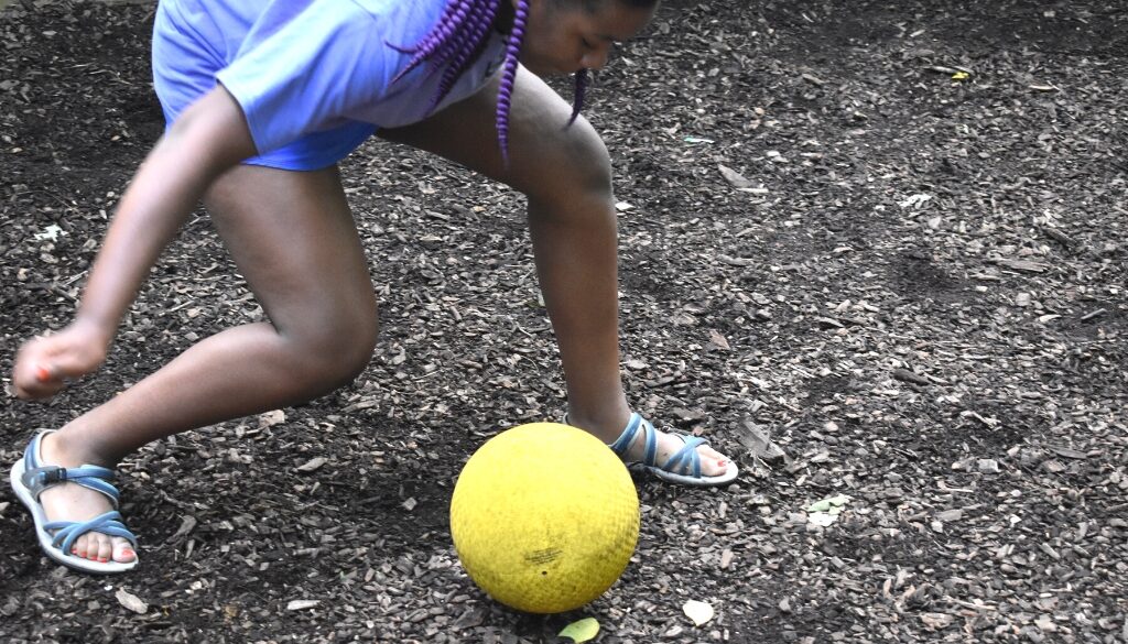 Una campista negra de Camp Kupugani golpeando la pelota GaGa en medio del juego.