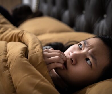 A teenage Asian girl laying in bed trying to manage childhood anxiety.