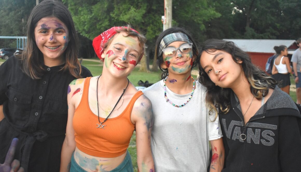 A small group of happy Camp Kupugani girl campers covered in colorful paint.