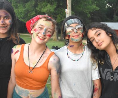 A small group of happy Camp Kupugani girl campers covered in colorful paint.