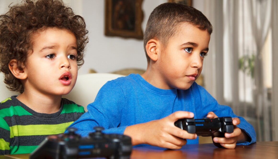 Two young boys playing video games intensely.