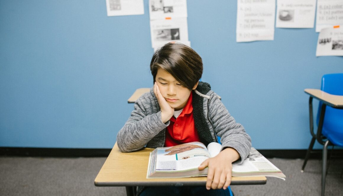 An Asian kid displaying low self-esteem in a classroom.