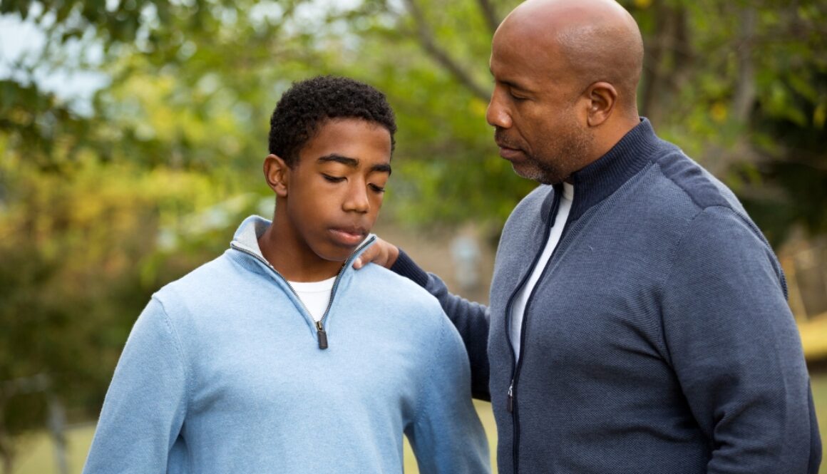A black father consulting his son with fear-based-parenting.