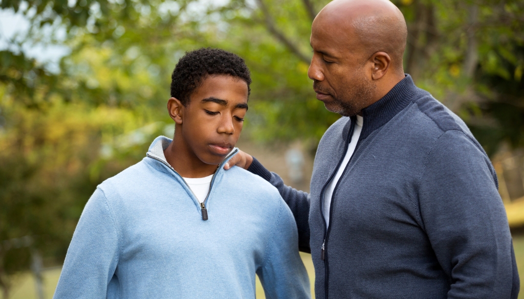 A black father consulting his son with fear-based-parenting.