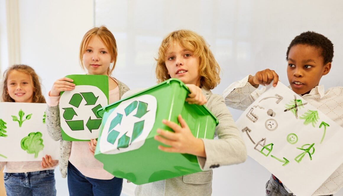 Children holding bins and paintings with recycling symbols.